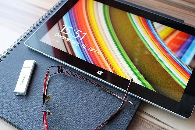 Tablet a USB flash disk ležící na zápisníku